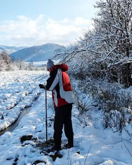 Inginer geotehnician efectuând măsurători pe teren, iarna, pentru evaluarea condițiilor de fundare.