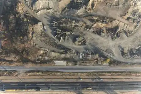 Scanare aeriană cu dronă a unei cariere industriale lângă drum și cale ferată – cartografiere topografică a terenului.